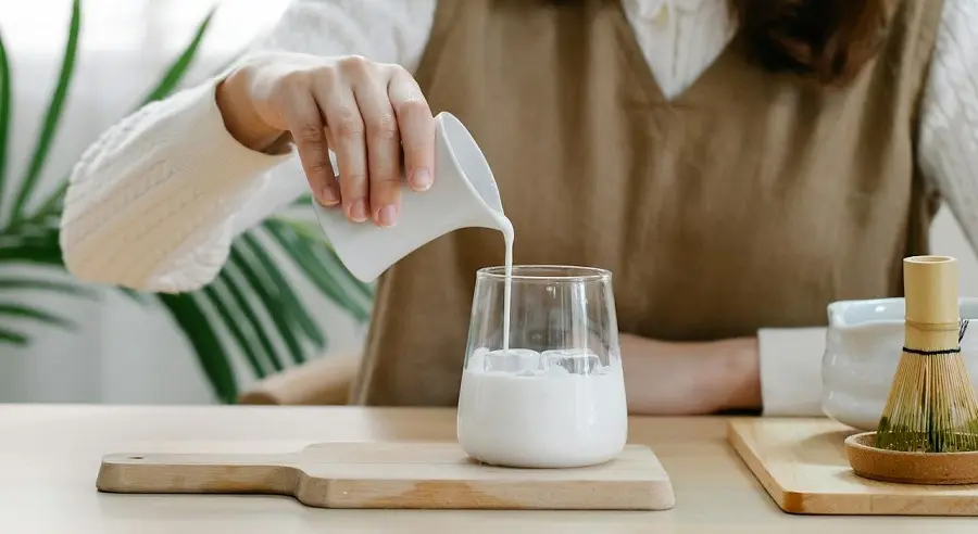 Ly sữa ấm trắng mịn được rót từ bình gốm giúp mẹ bỉm sữa cải thiện chất lượng sữa sau sinh