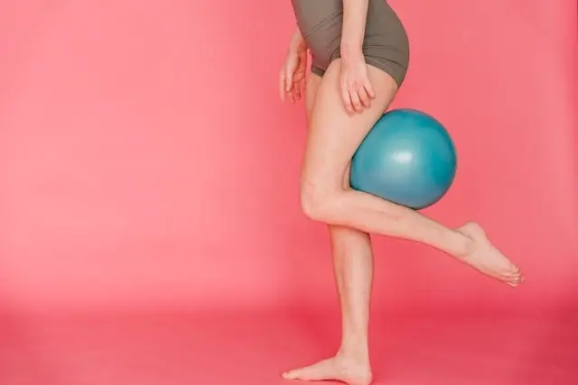 Phụ nữ tập luyện kẹp bóng thể dục giữa hai chân để làm thon gọn bắp chân và đùi