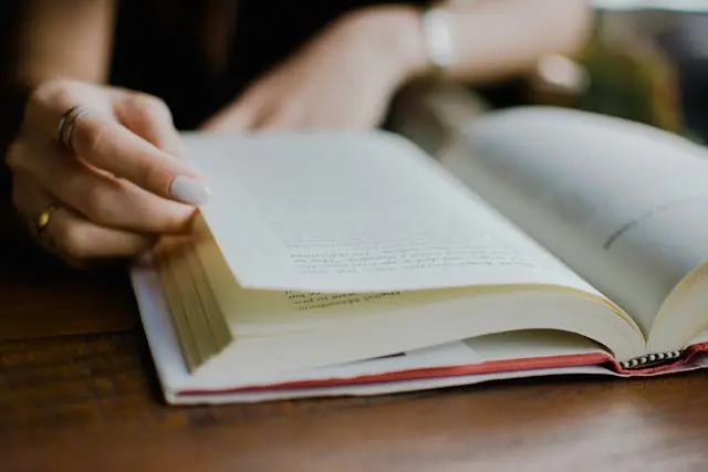 Một người đang ngồi đọc sách bên cửa sổ trong một không gian yên tĩnh và ấm áp để thư giãn tâm hồn