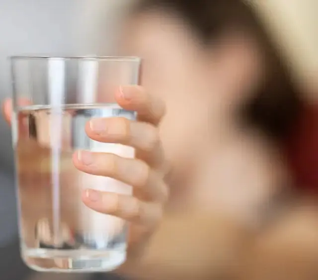 Người phụ nữ uống ly nước ấm vào buổi sáng để thanh lọc gan và thận.