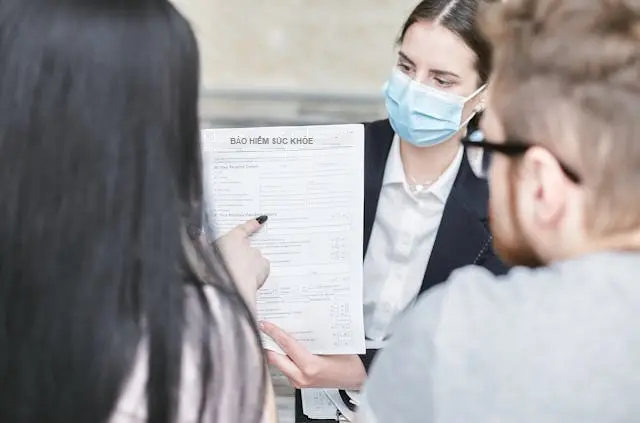 Nhân viên tư vấn đang giải thích các điều khoản trong hợp đồng bảo hiểm sức khỏe cho khách hàng để làm thủ tục thanh toán