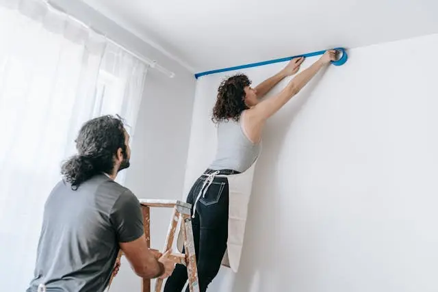 Người thuê nhà đang dán băng dính sơn lên tường để chuẩn bị tự sơn sửa và cải tạo lại phòng khách